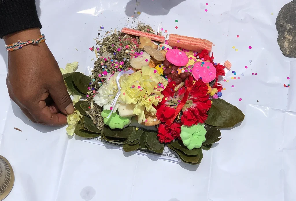 Paqo assembling despacho ceremony ingredients into a mandala on white paper